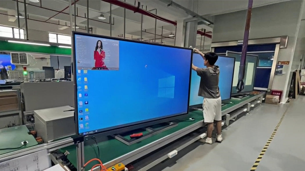 A worker next to powered-on displays on an assembly line